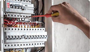 Electrician using voltage tester on circuit breaker panel, electrical maintenance and safety