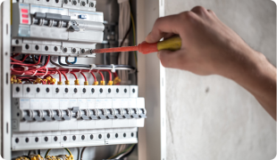 Electrician using voltage tester on circuit breaker panel, electrical maintenance and safety